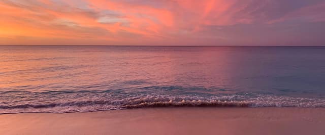 Bahamas beach at sunset with pink and orange sky reflecting on calm water