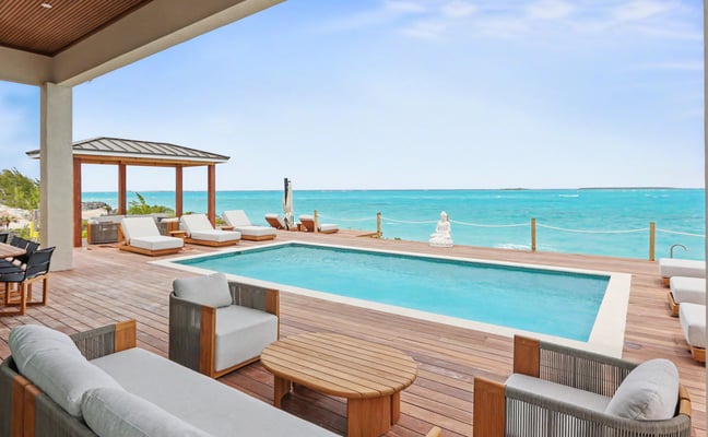 Pool deck with sun loungers overlooking turquoise Exuma waters